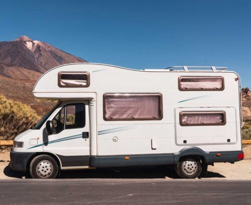 camper-van-on-road-near-hill-and-blue-sky-2021-12-09-12-34-12-utc
